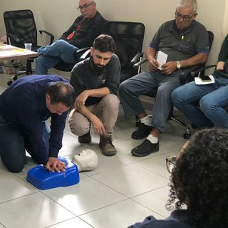 Turma praticando reanimação cardiopulmonar em manequim