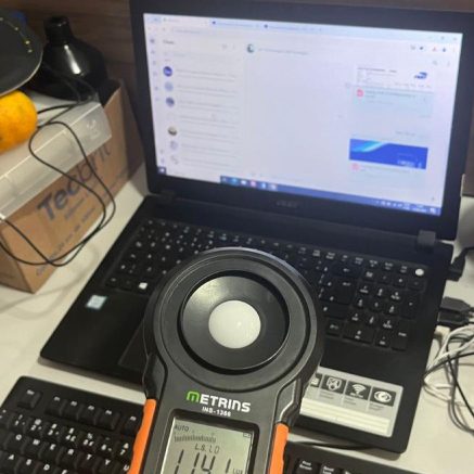 Luxímetro ao lado de notebook durante avaliação de iluminação